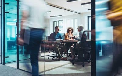 Group of business persons having a meeting in a closed glass conference room