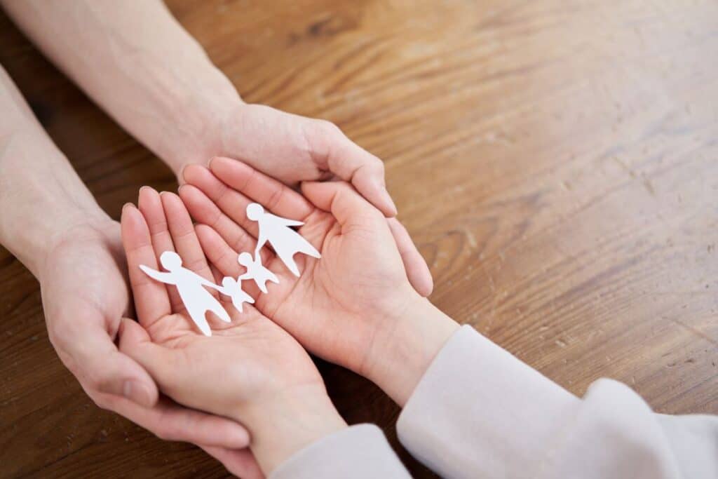 Man and woman's hands holding paper chain of a family