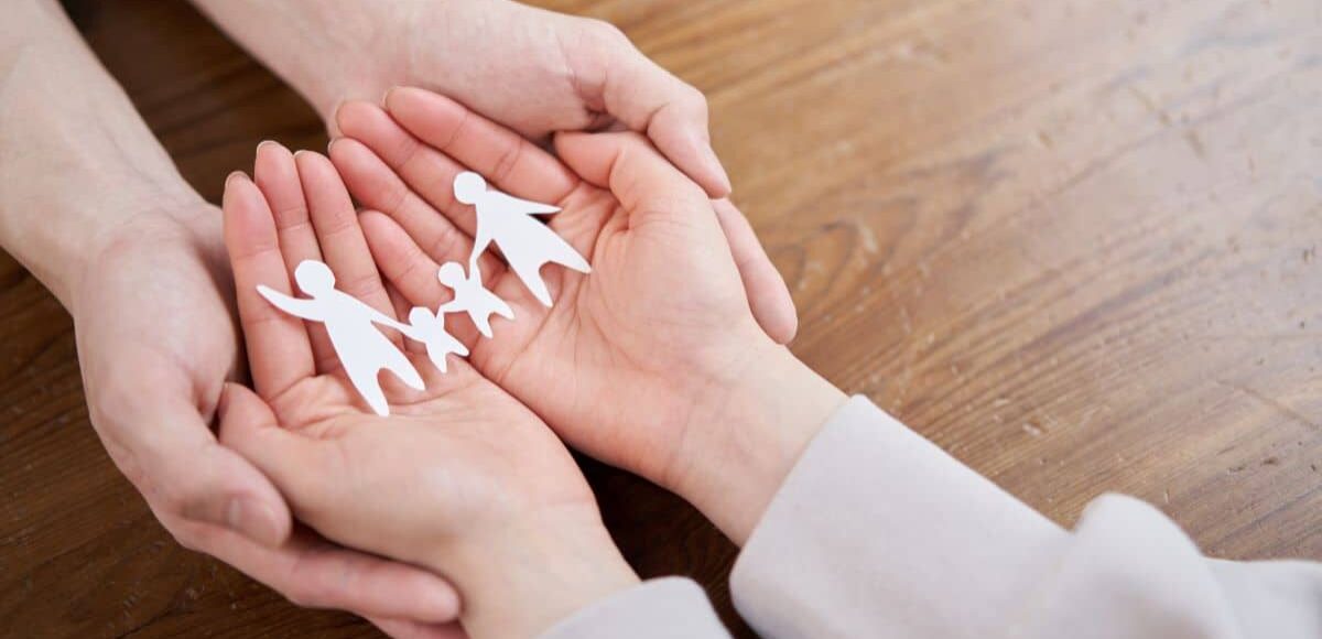 Man and woman's hands holding paper chain of a family