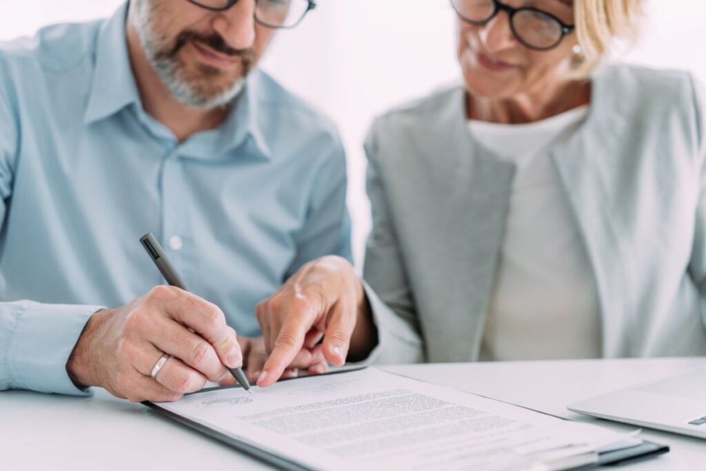 Couple in front of a document with the man signing it