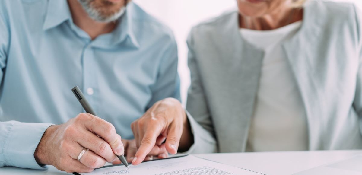 Couple in front of a document with the man signing it