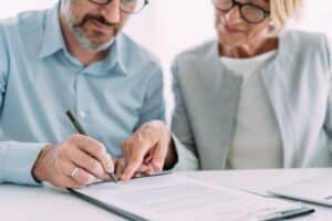 Couple in front of a document with the man signing it