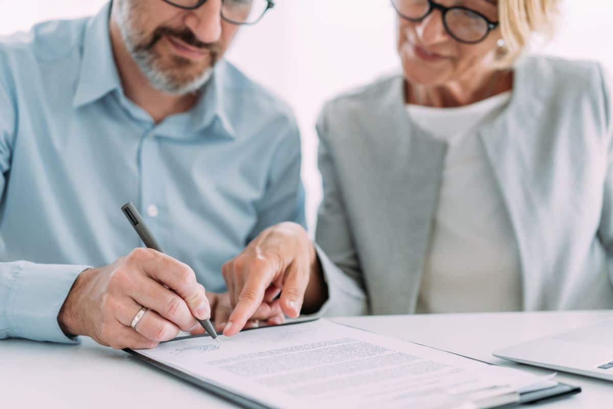 Couple in front of a document with the man signing it